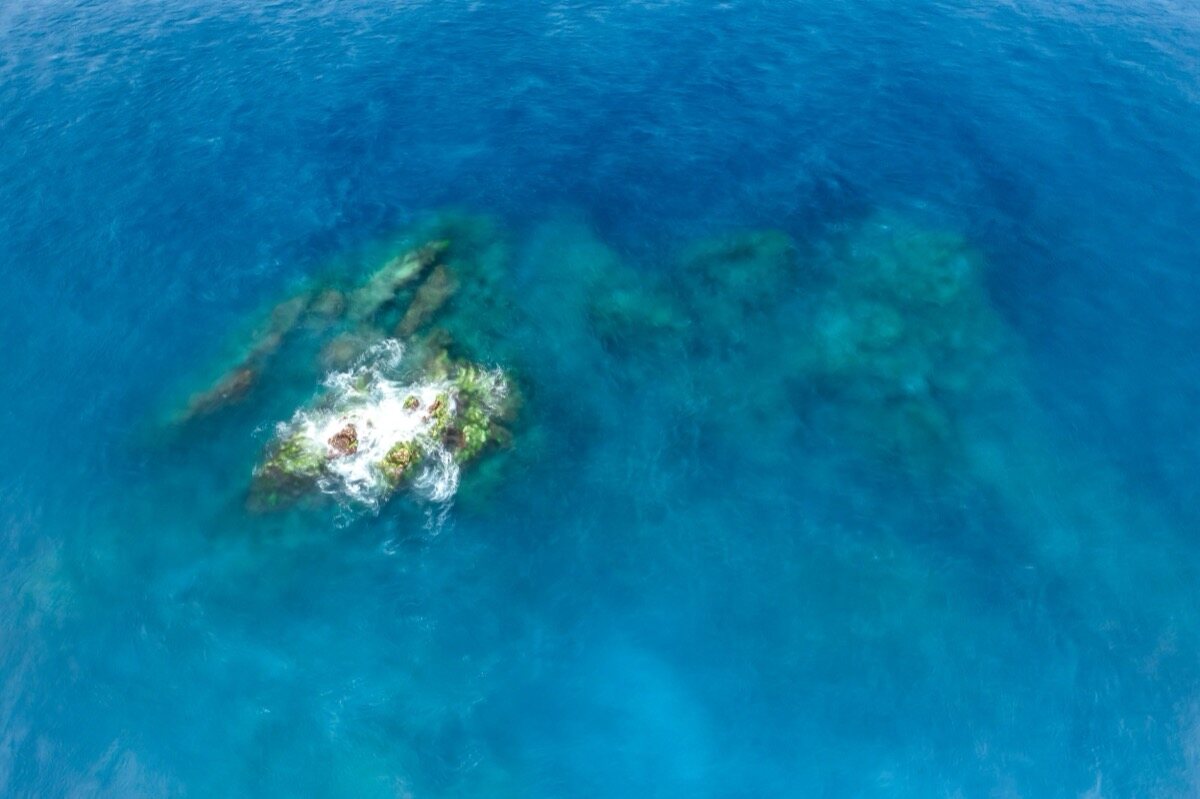 Vista cenital de la roca de Richelieu Rock asomando en agua azul